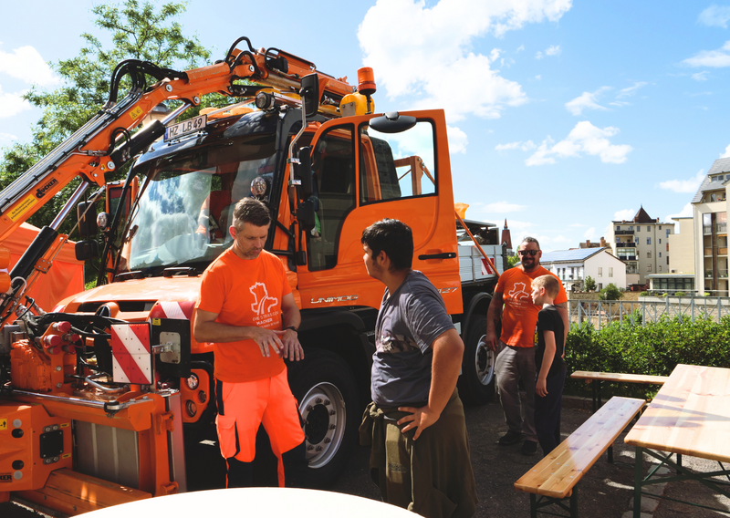 Unimog im Hintergrund, Betriebsdienstler unterhalten sich mit Interessenten