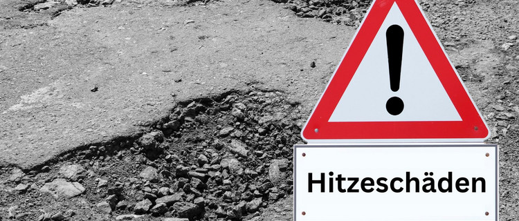 Verkehrsschild mit der Aufschrift "Hitzeschäden" vor kaputtem Asphalt