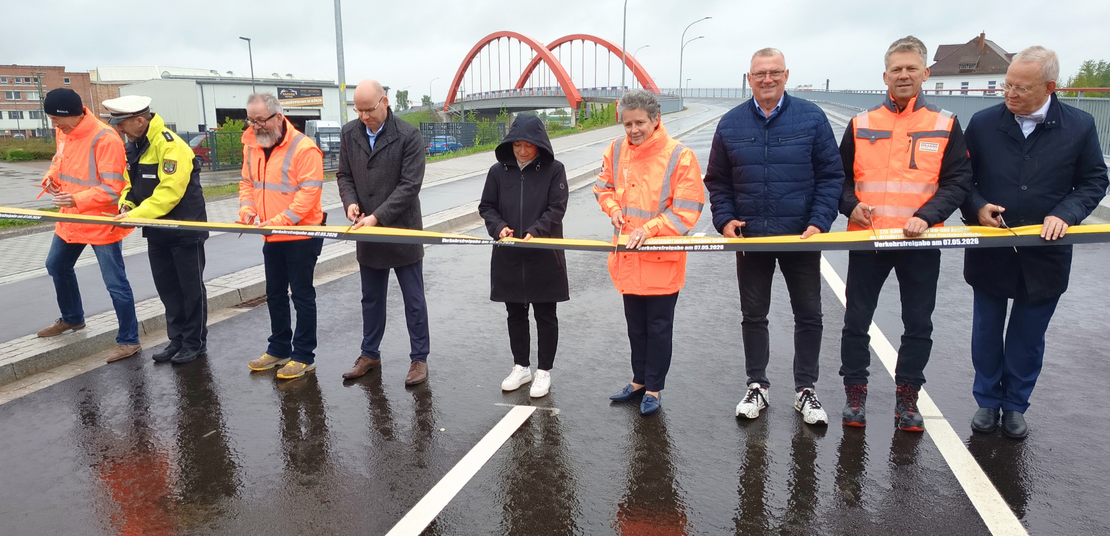 Ein Band wird von einer Gruppe von Menschen symbolisch zur Verkehrsfreigabe der Maßnahme durchgeschnitten.