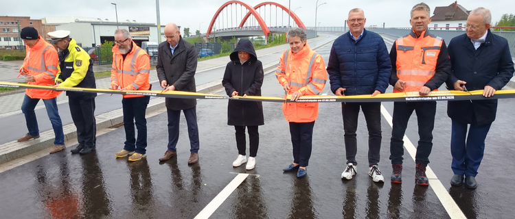Ein Band wird von einer Gruppe von Menschen symbolisch zur Verkehrsfreigabe der Maßnahme durchgeschnitten.