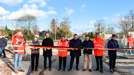 Geladene Gäste durchschneiden auf der neuen Ortsumgehung das Band für die symbolische Freigabe der Straße