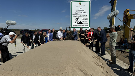 Spatenstich an der Baustelle vor dem Bauschild