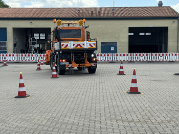 Schneepflug fährt rückwärts durch eine Gasse. 