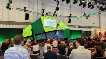 Besucher sitzen vor einem Podium und hören einen Vortrag